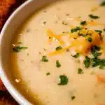 Bowl of easy potato soup topped with herbs and served with bread
