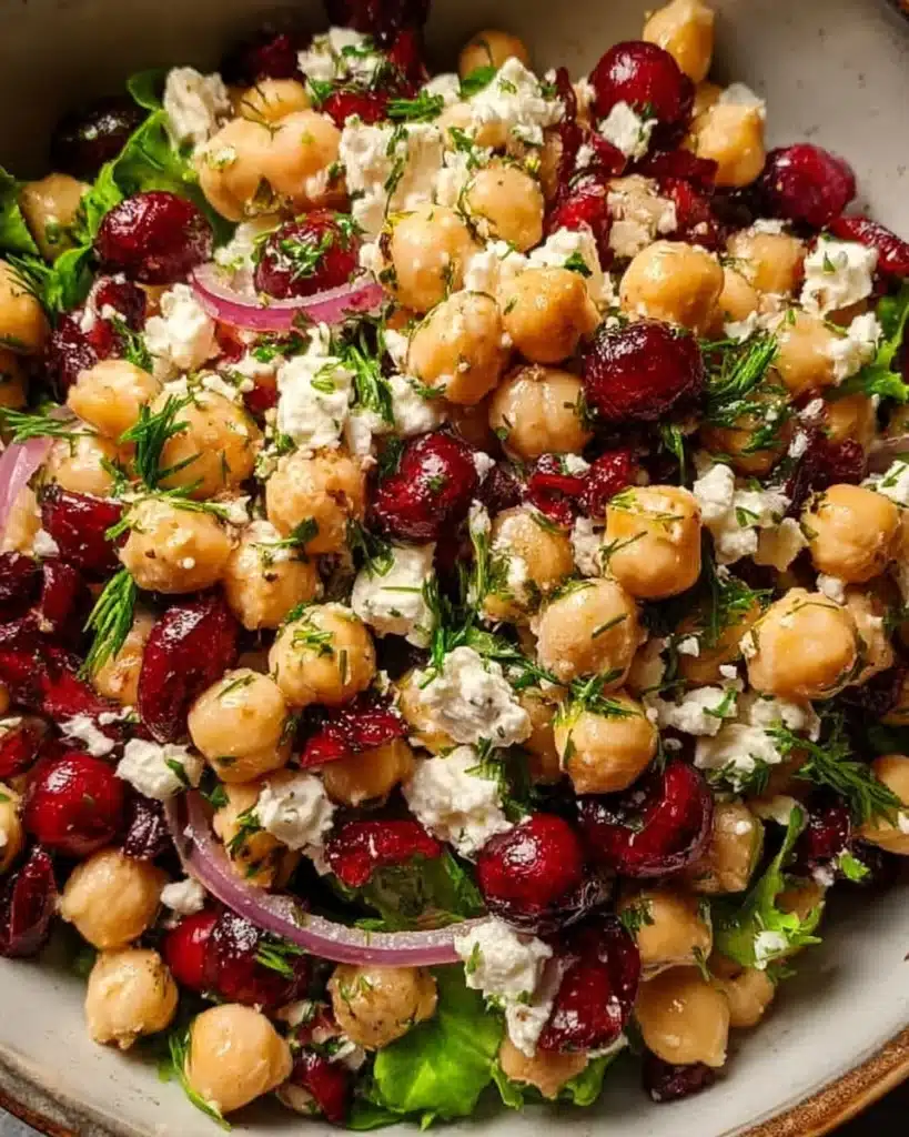 Feta and Cranberry Chickpea Salad in a bowl, garnished with fresh herbs.