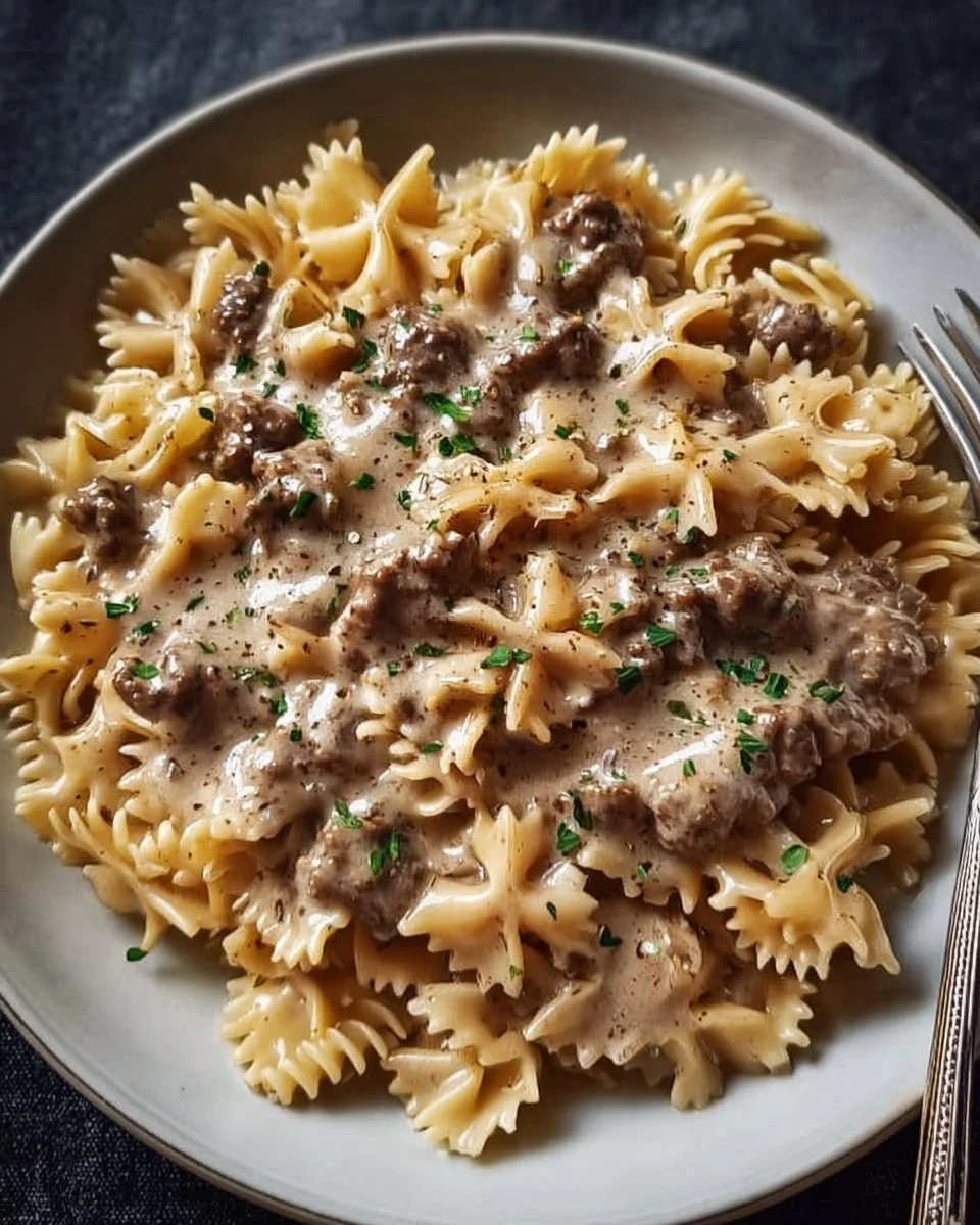 Creamy beef pasta dish garnished with herbs on a plate