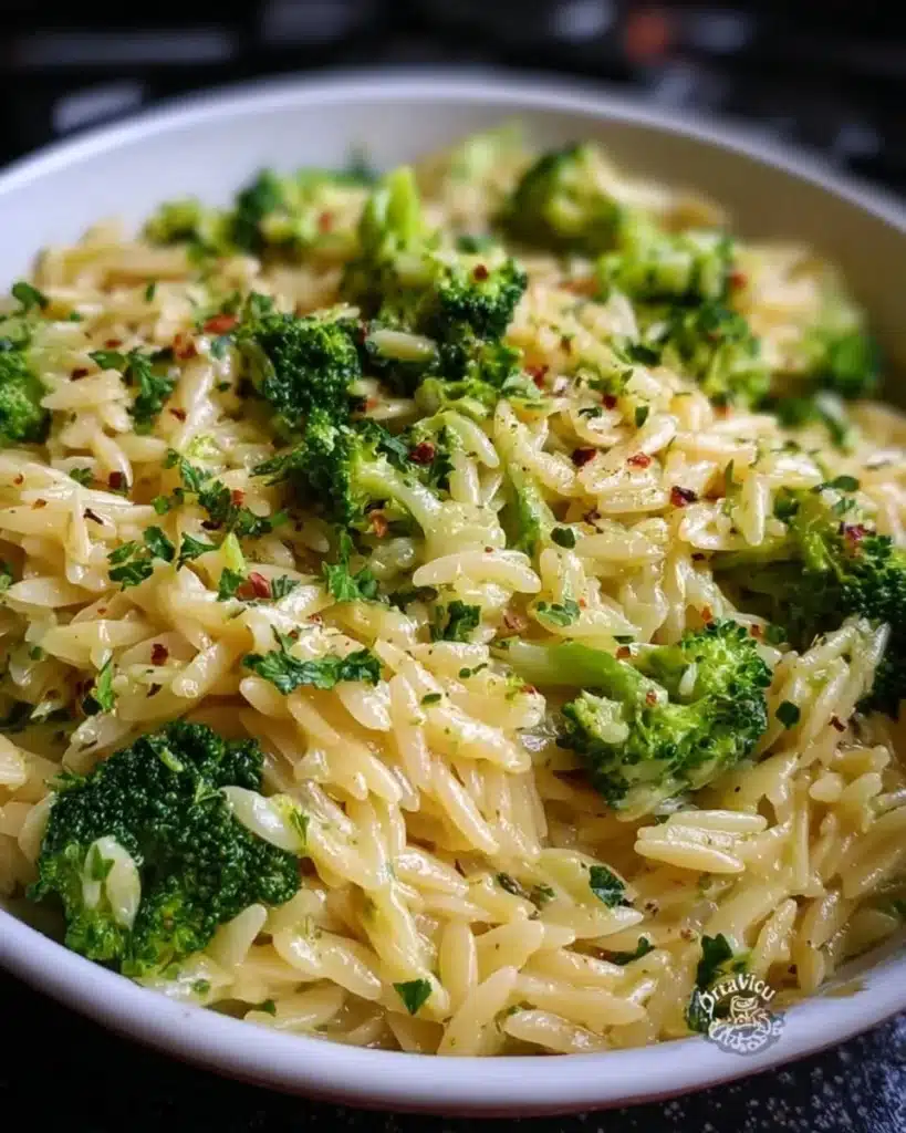 Creamy one pot broccoli cheese orzo dish topped with melted cheese and broccoli.
