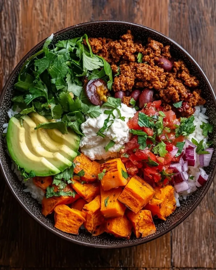 Colorful sweet potato taco bowl with toppings including avocado and salsa.