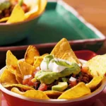 A delicious serving of Mexican nachos baskets topped with cheese and salsa.