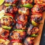 Grilled BBQ chicken skewers on a platter with fresh vegetables