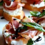Burrata and prosciutto crostini topped with fresh herbs and drizzled with balsamic glaze