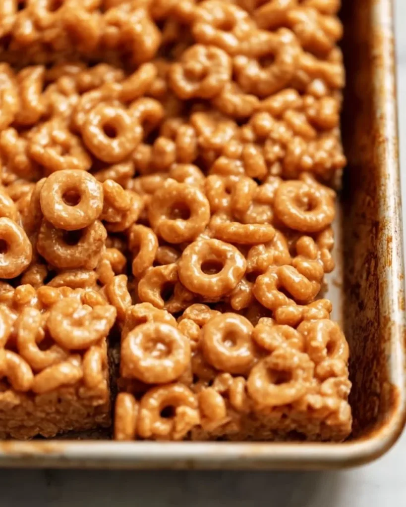 Peanut Butter Cheerio Bars on a plate with ingredients in the background